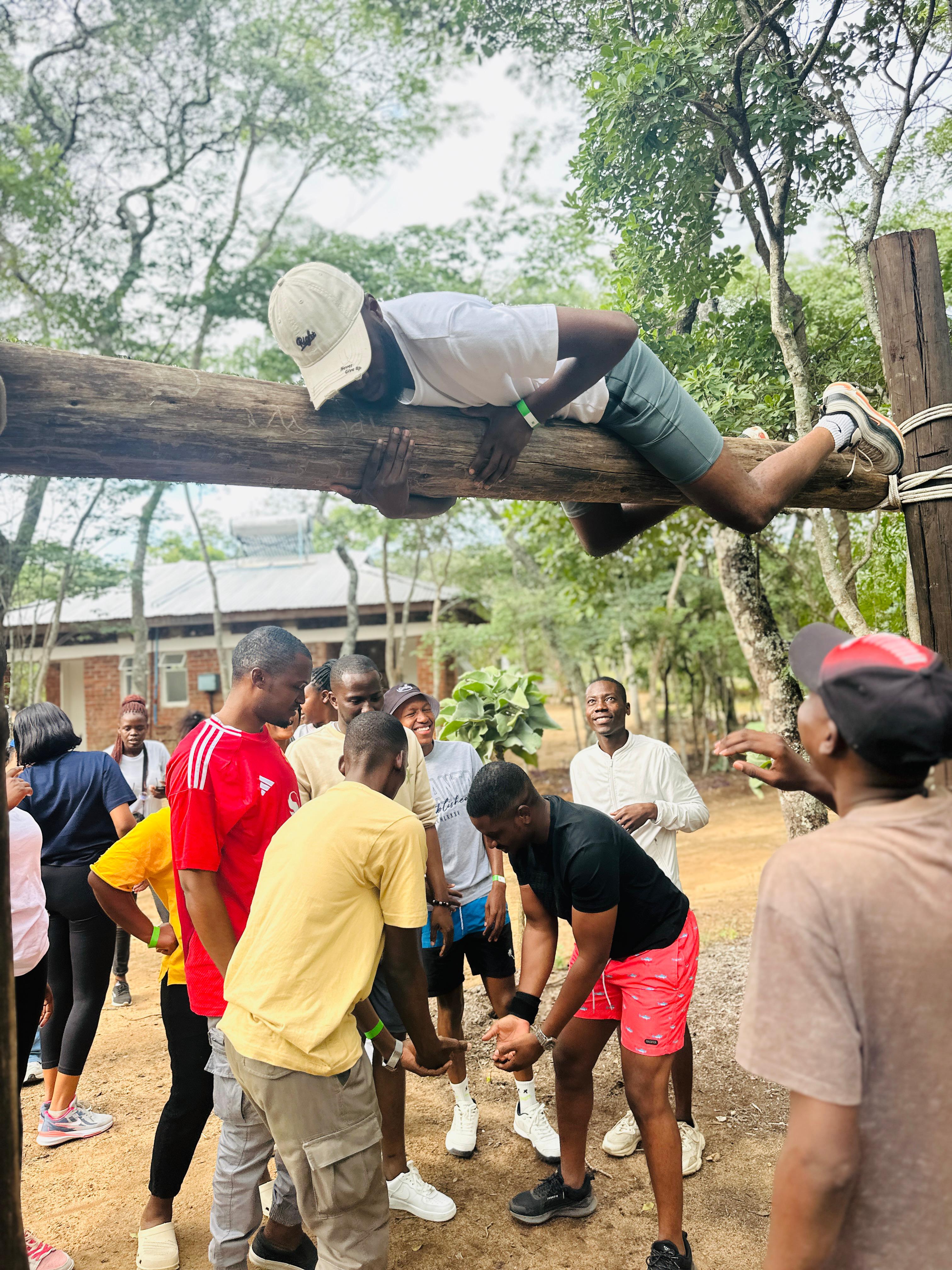 Camp participant balancing across a wooden obstacle while teammates stand nearby
