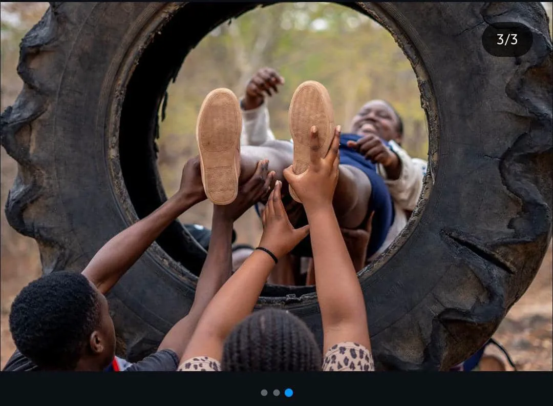 Camp participants helping someone through a large tyre obstacle