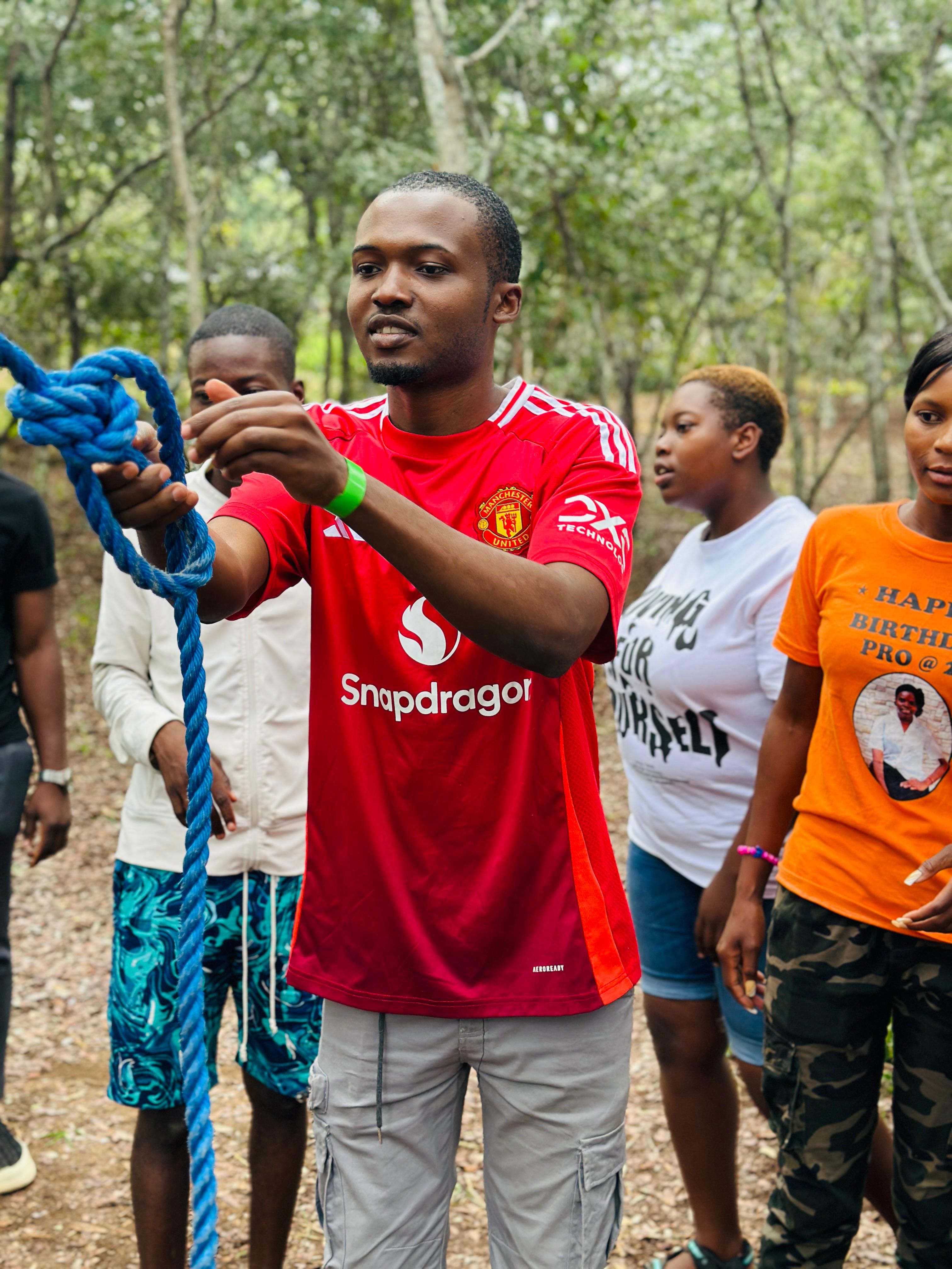 Camp participant tying a blue rope as teammates watch