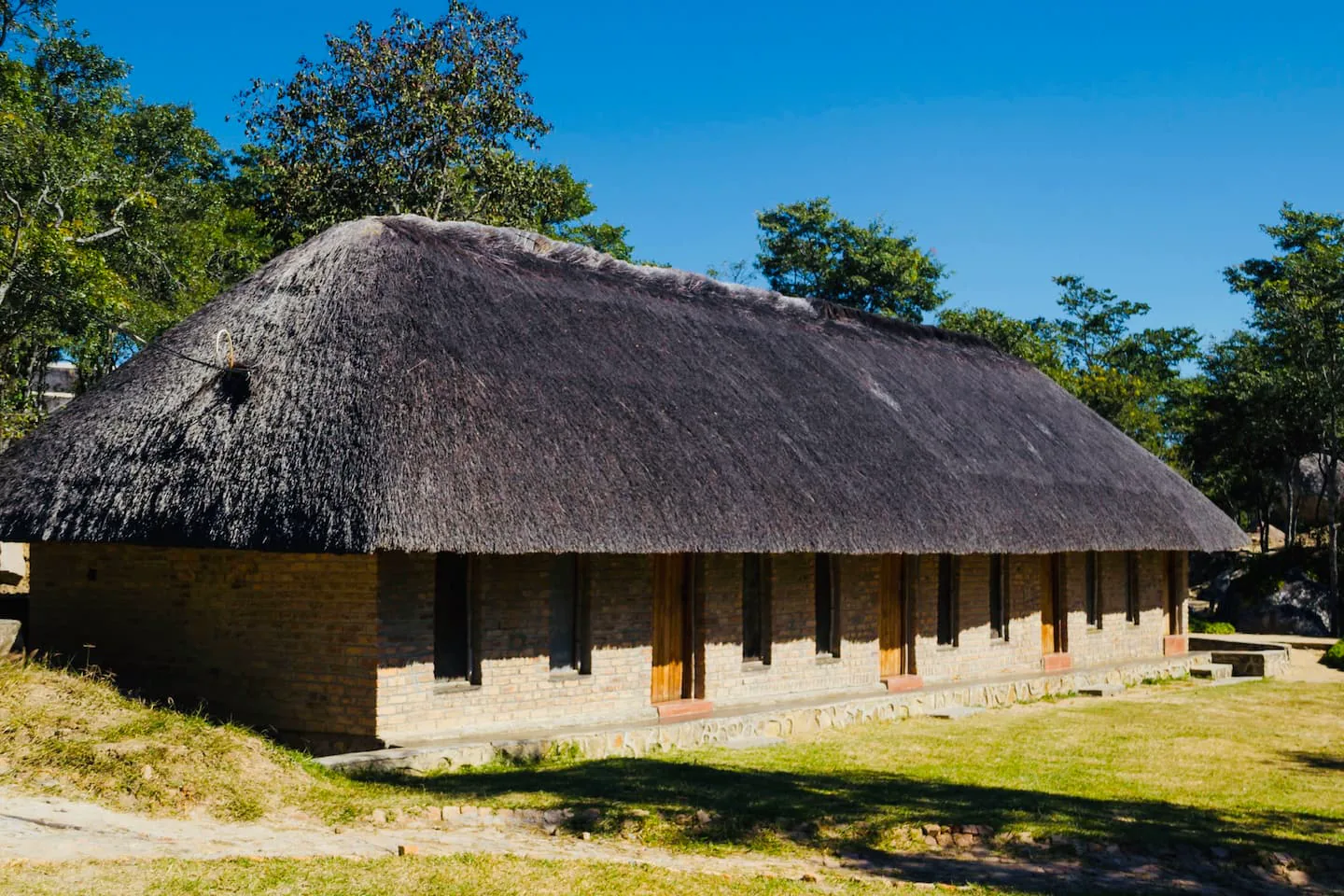 Thatched accommodation block surrounded by trees at Karumazondo Resort